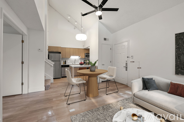 A modern living room with a dining area and a kitchen in the background.