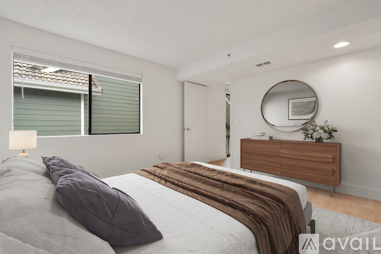 A bedroom with a large bed, a dresser, and a round mirror on the wall.
