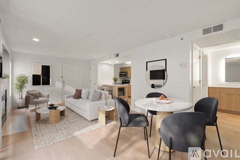 A modern living room with a white sofa, a coffee table, and a dining table with chairs.