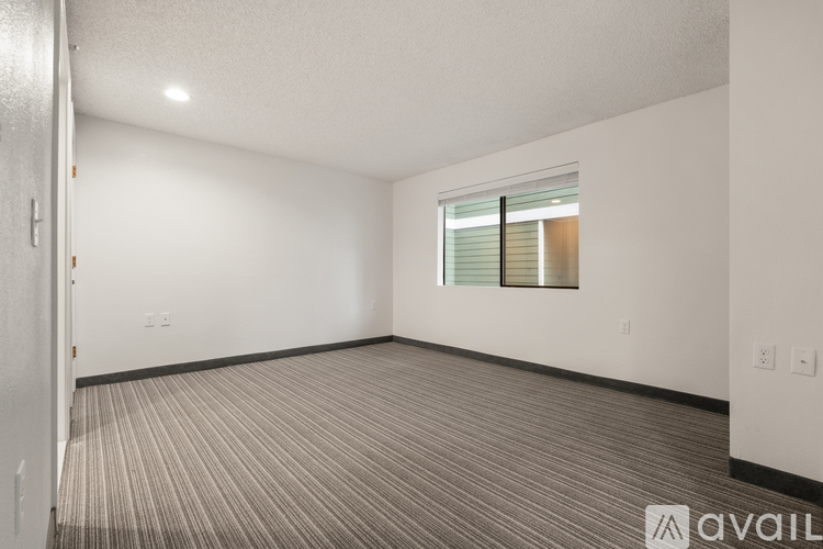 A room with a carpeted floor and a window with blinds.