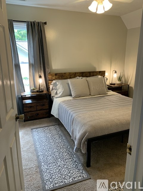 A bedroom with a bed, nightstands, and a window with curtains.