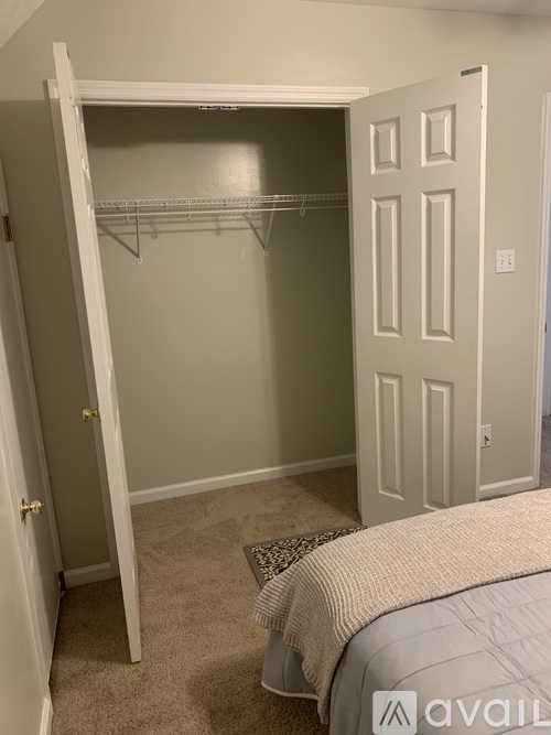 A bedroom with a bed, a closet with a white door, and a carpeted floor.