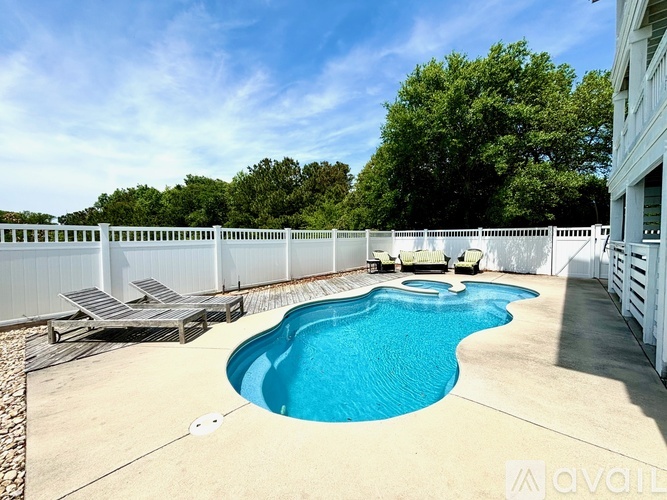 A pool with a slide and sun loungers.