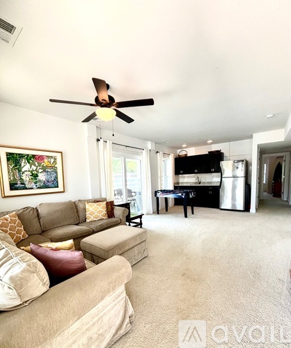 A living room with a brown sofa and a ceiling fan.