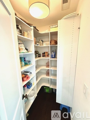 A small, well-organized kitchen with white cabinets and shelves.