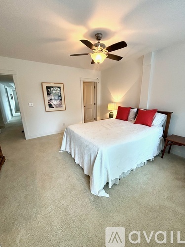 A bedroom with a bed, a ceiling fan, and a picture on the wall.