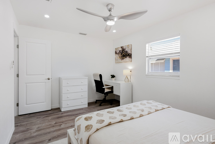 A bedroom with a bed, a chair, a dresser, and a ceiling fan.