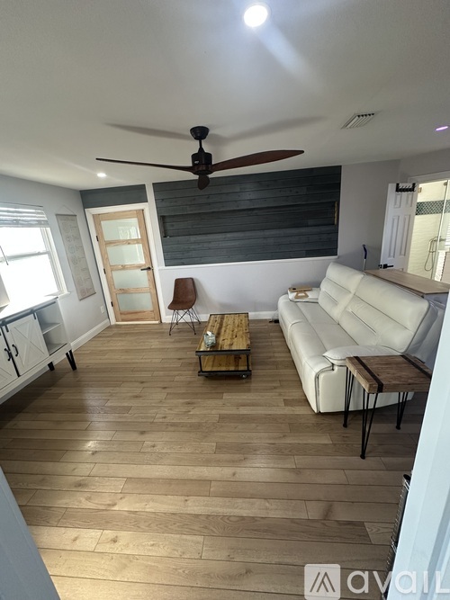 A living room with a white couch and wooden floors.