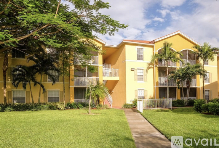 A yellow apartment building with a green lawn in front.
