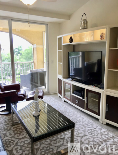 A living room with a glass coffee table and a television on a stand.