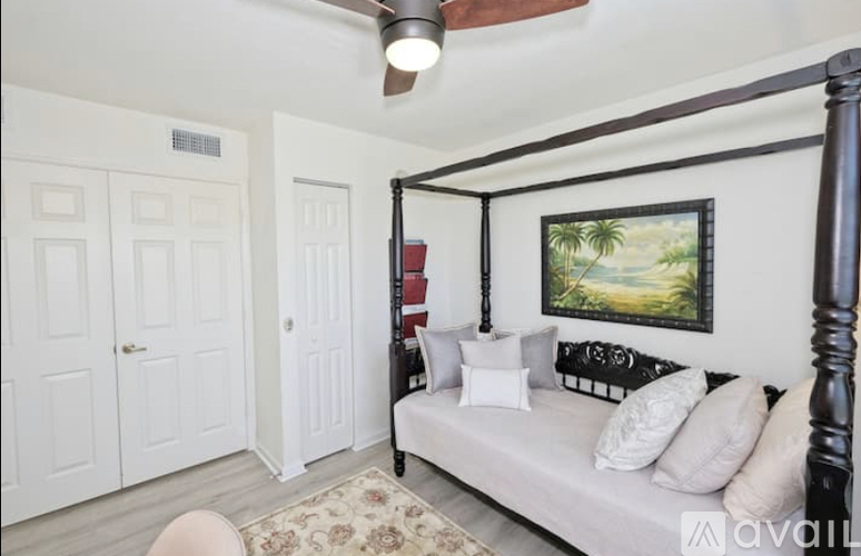 A bedroom with a four poster bed and a painting on the wall.