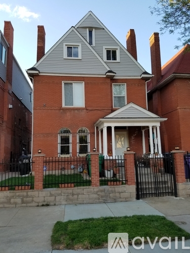 A brick house with a porch and a black fence.