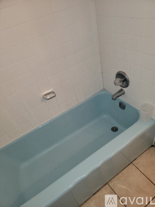 A blue bathtub in a bathroom with white tiles.