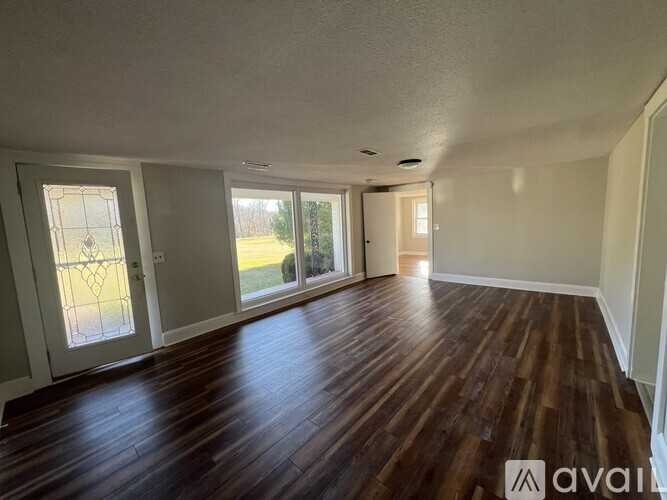 A room with wooden flooring and a large window.