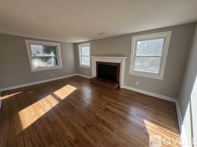 A room with wooden floors and three windows.