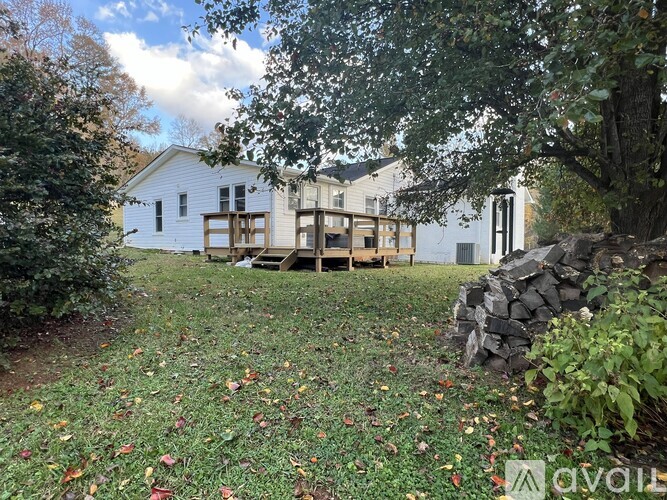 A white house with a porch and a stone wall in front.