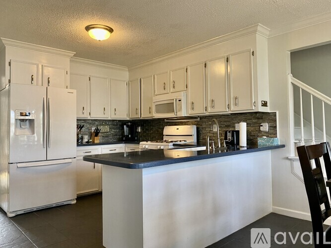 A kitchen with white cabinets and a black countertop.