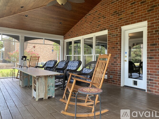 A wooden rocking chair is in front of a brick building.