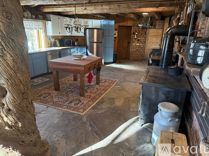 A rustic kitchen with a wooden table and a rug on the floor.