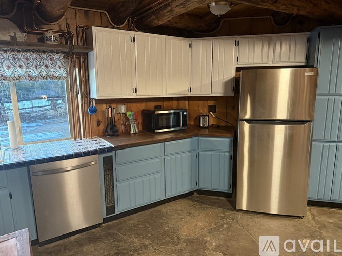 A kitchen with a stainless steel refrigerator and cabinets.