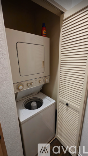 A small white washing machine and dryer in a small laundry room.