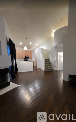 A spacious room with wooden floors and a staircase.