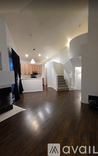 A spacious room with wooden floors and a staircase.