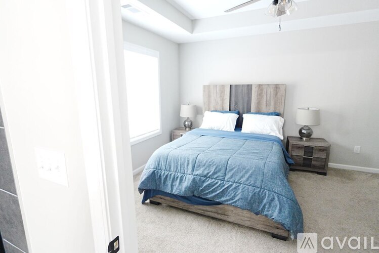 A bedroom with a bed, two lamps, and a ceiling fan.