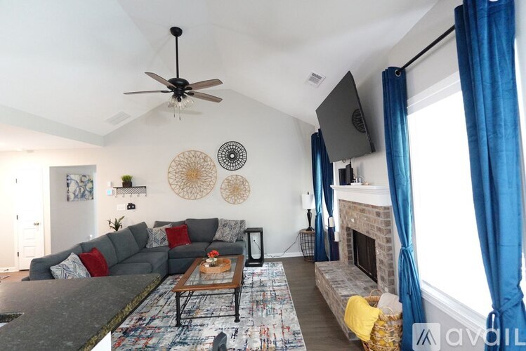 A living room with a grey couch, a coffee table, a fireplace, and a ceiling fan.