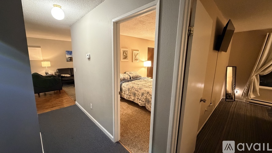 A bedroom with a bed, a couch, a chair, a lamp, and a window with curtains.