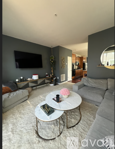A living room with a grey couch, a white coffee table, and a flat screen TV mounted on the wall.