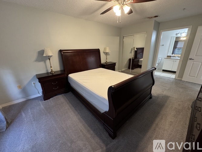 A bedroom with a large bed, two nightstands with lamps, and a ceiling fan.