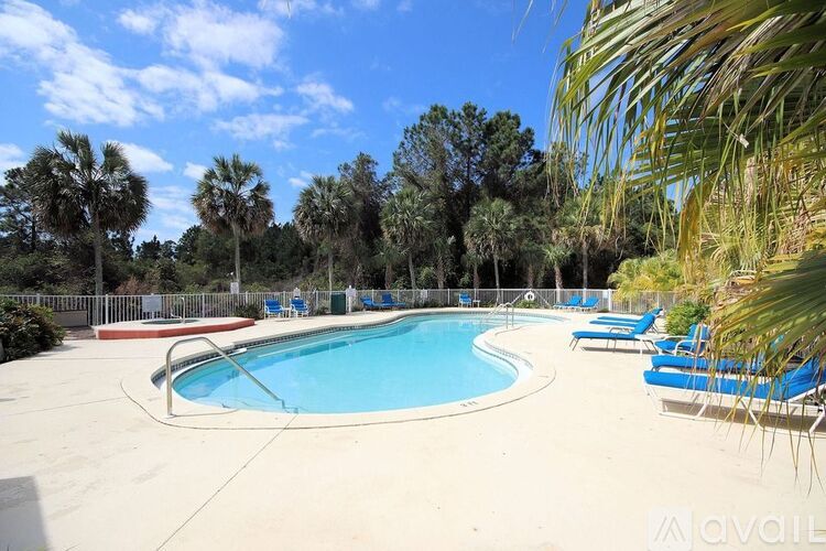 A large outdoor swimming pool surrounded by trees and lounge chairs.
