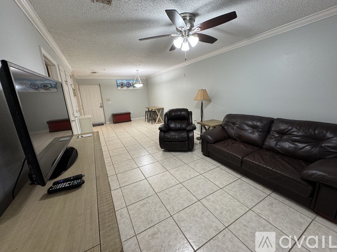 A living room with a black leather couch and a television.