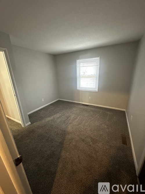 A carpeted room with a window and a door.