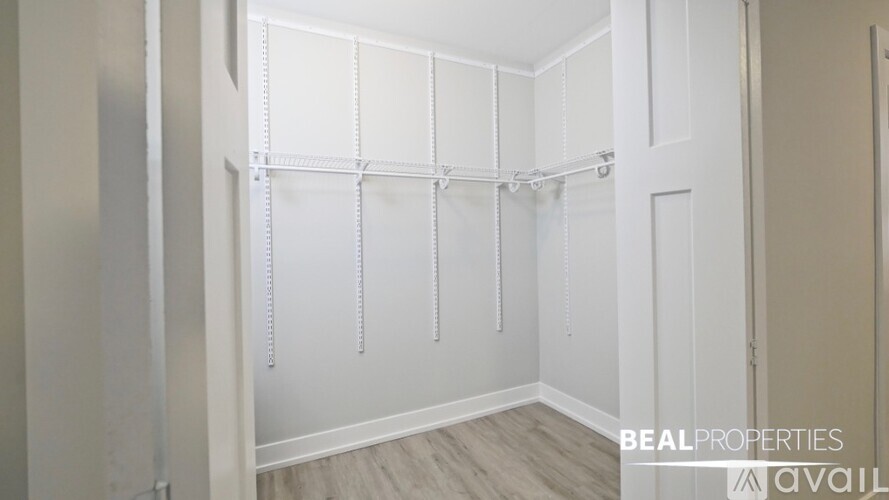 A white closet with a white door and a white shelf.