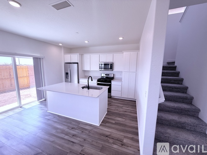 A modern kitchen with white cabinets and a white island with a sink.