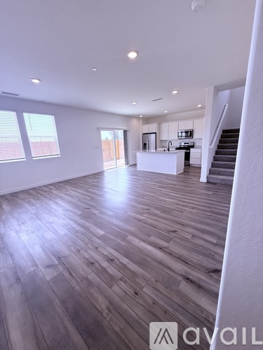 A spacious room with wooden flooring and a staircase leading to the upper level.