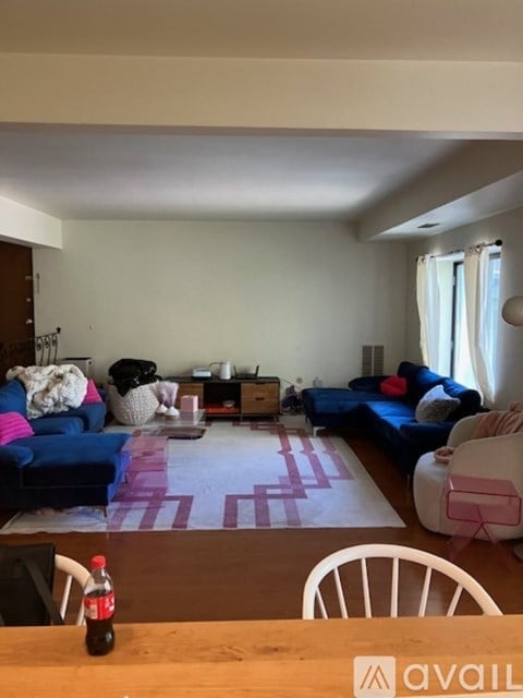 A living room with a blue couch and a pink rug.