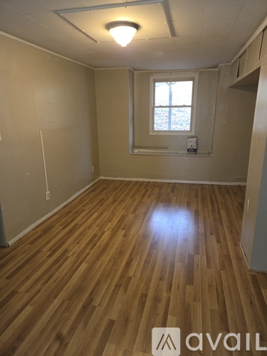 A room with wooden flooring and a window.