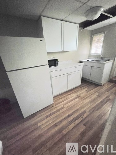 A kitchen with white appliances and wooden floors.