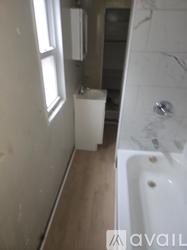A white toilet sits in a bathroom next to a bathtub.