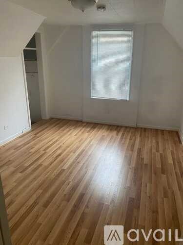A room with wooden flooring and a window with blinds.