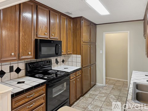 A kitchen with wooden cabinets and black appliances.