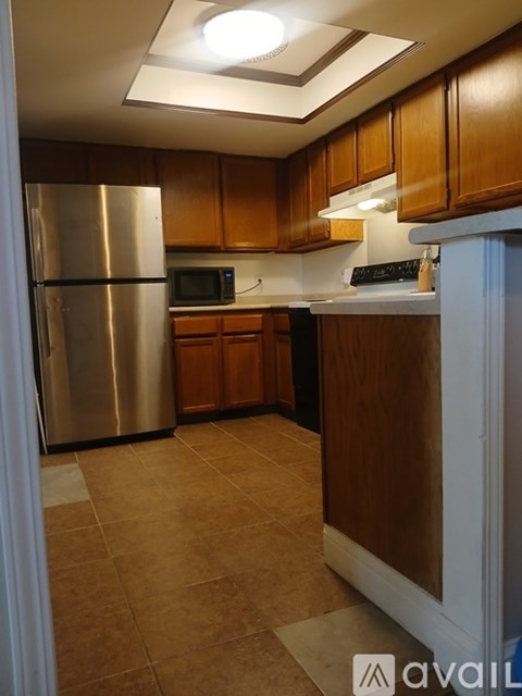 A kitchen with wooden cabinets and a stainless steel refrigerator.