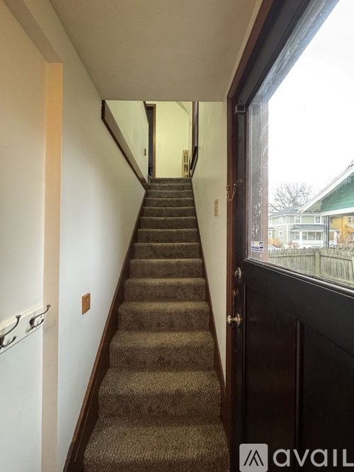 A staircase with a carpeted runner and a black door at the bottom.