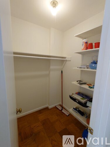 A white closet with a white shelf and a white door.