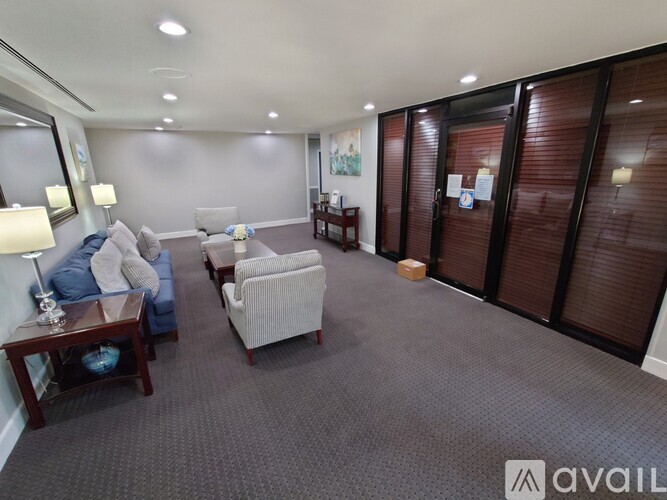 A spacious waiting room with a grey carpet and wooden furniture.