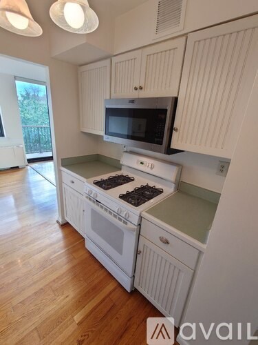 A kitchen with white cabinets and a wooden floor.
