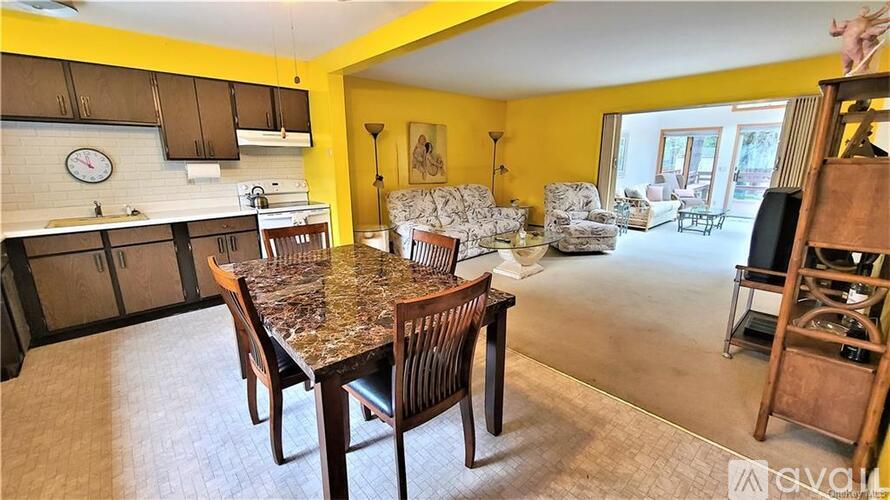A kitchen with a table and chairs in the foreground and a living room in the background.